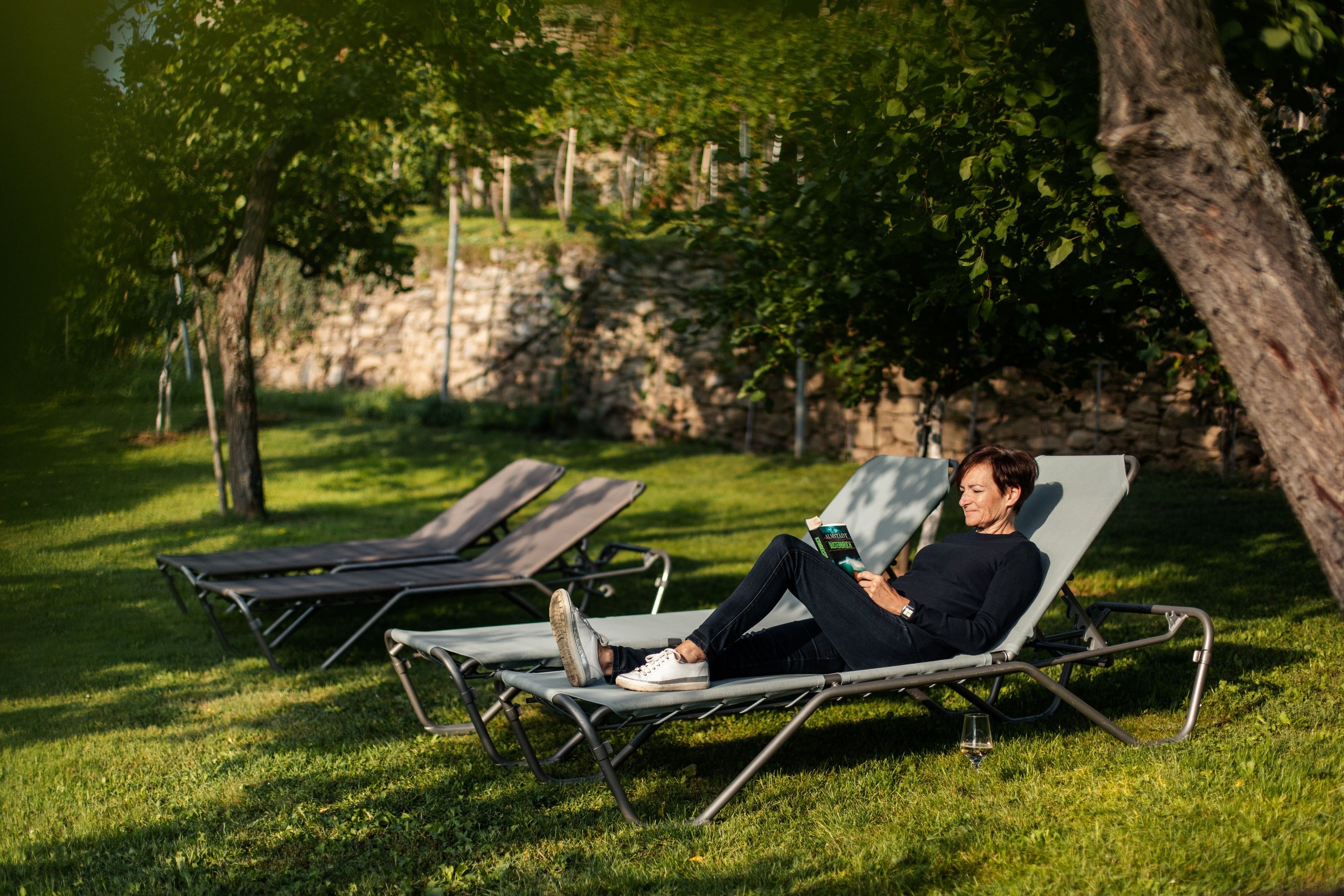 Egy személy a kertben egy napozóágyon olvas.