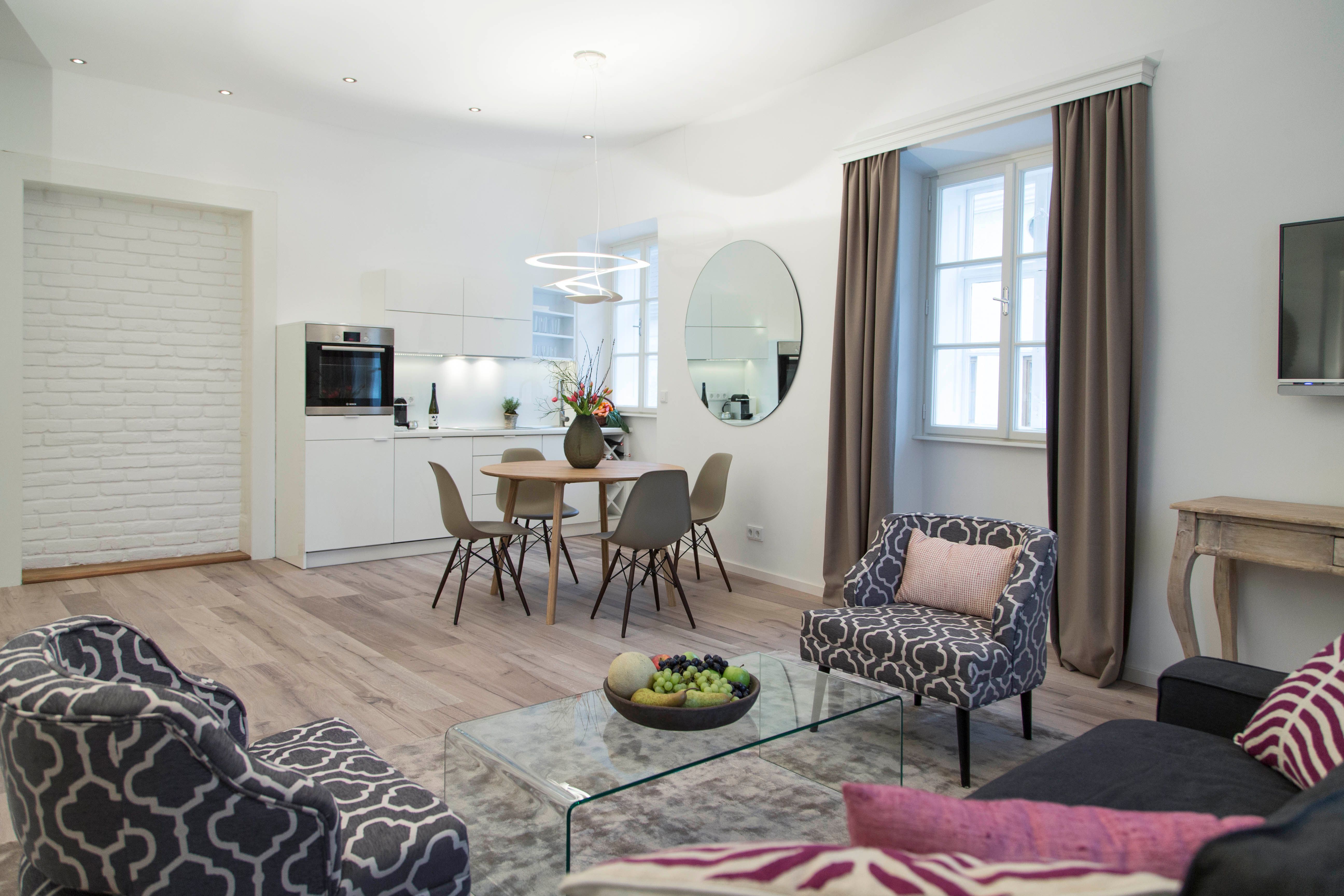 Modern nappali konyhával, étkezőasztallal és stílusos bútorokkal.