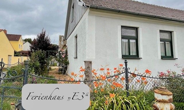 Egy fehér nyaraló külső nézete kerttel és virágokkal.