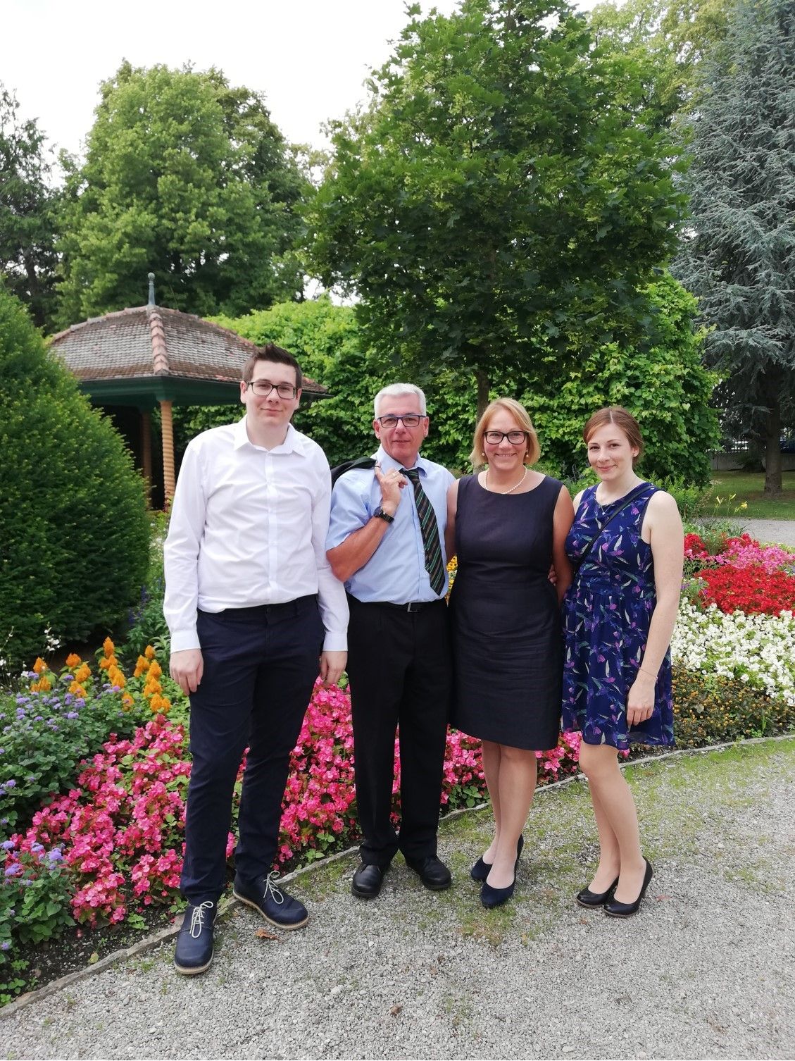 Négy ember áll egy kültéri virágágyás előtt.