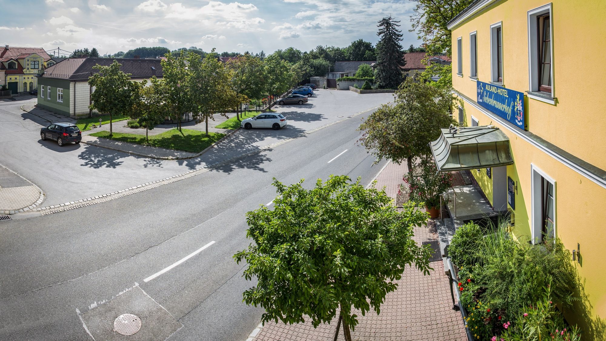 Utcai jelenet sárga épület és parkoló, fák és autók.