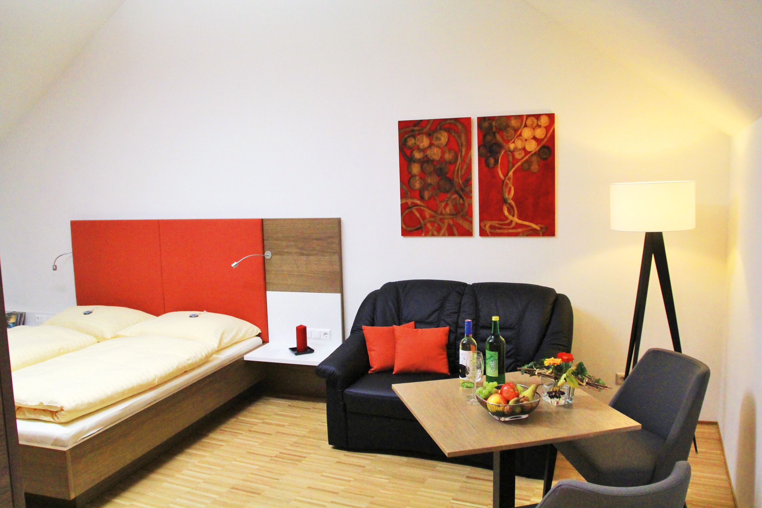 Hangulatos szoba franciaággyal, kanapéval, asztallal és állólámpával.