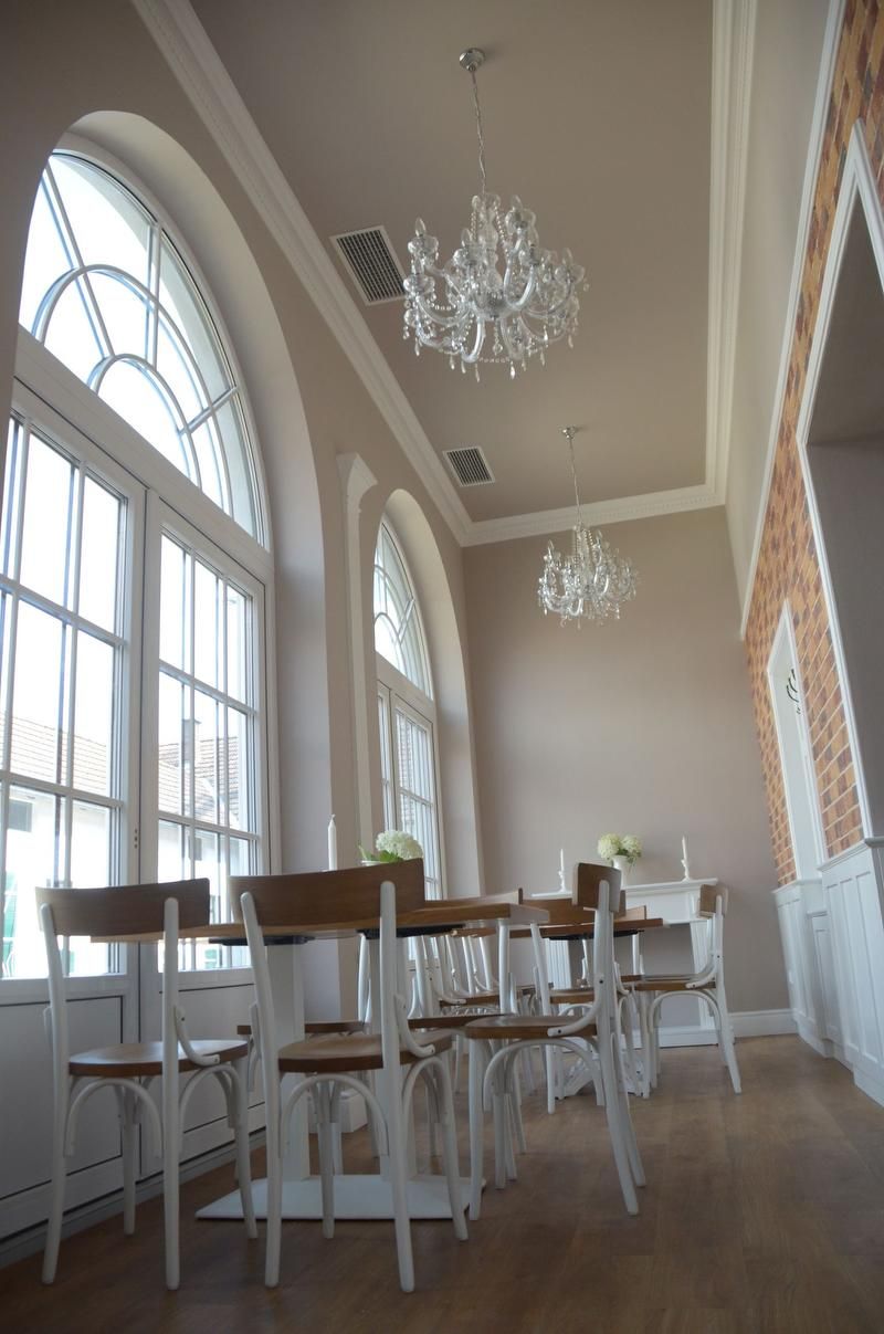 Elegáns szoba magas ablakokkal, csillárokkal és fabútorokkal.