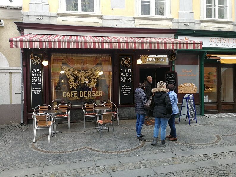 A Cafe Berger külső nézete a bejárat előtti ülőhelyekkel és emberekkel.