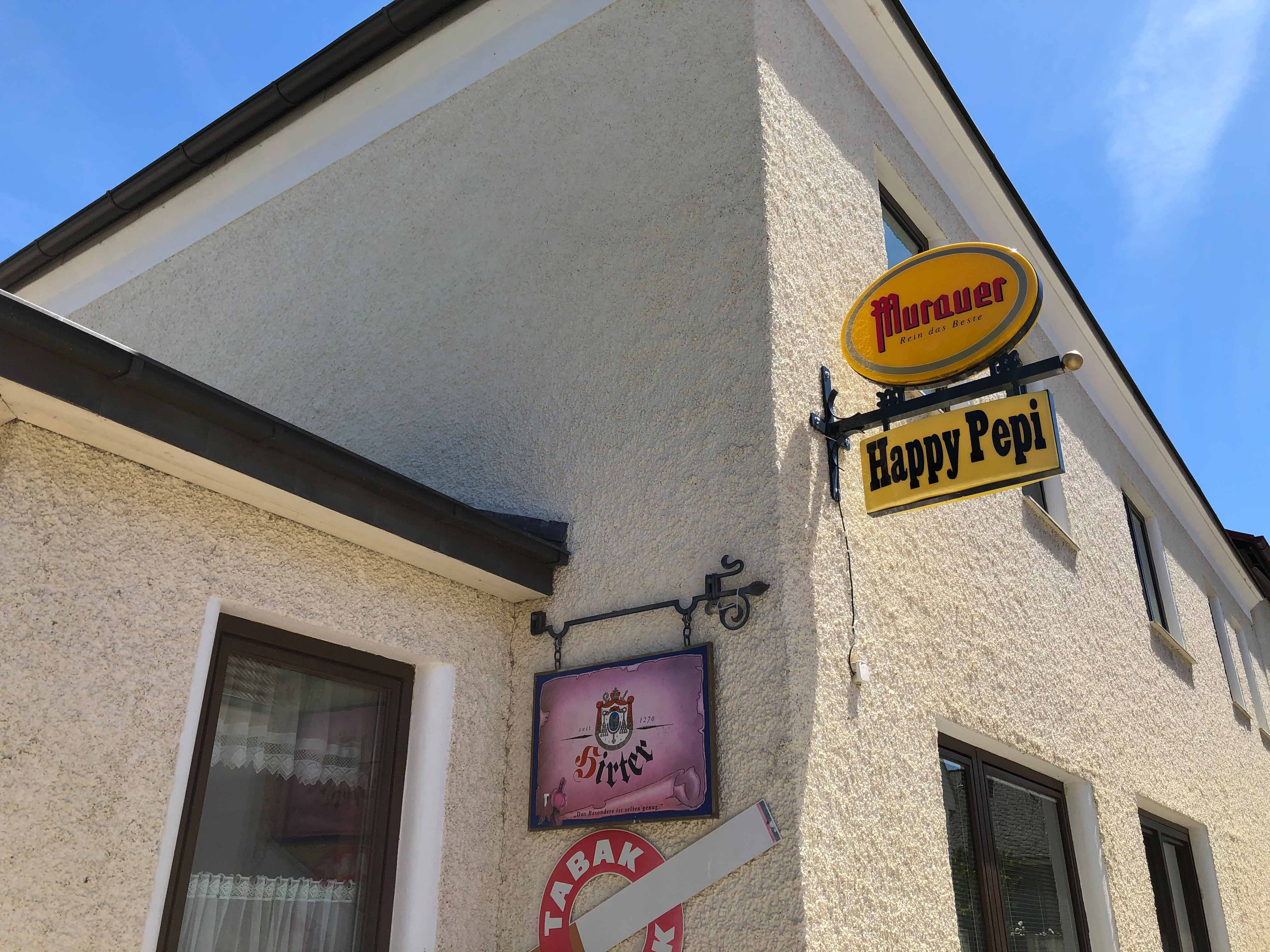 Egy épület külső nézete a "Murauer" és a "Happy Pepi" feliratokkal.