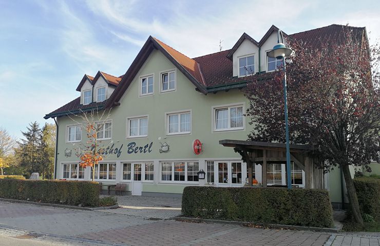 A "Gasthof Bertl" feliratú kétszintes épületet fák és bokrok veszik körül.