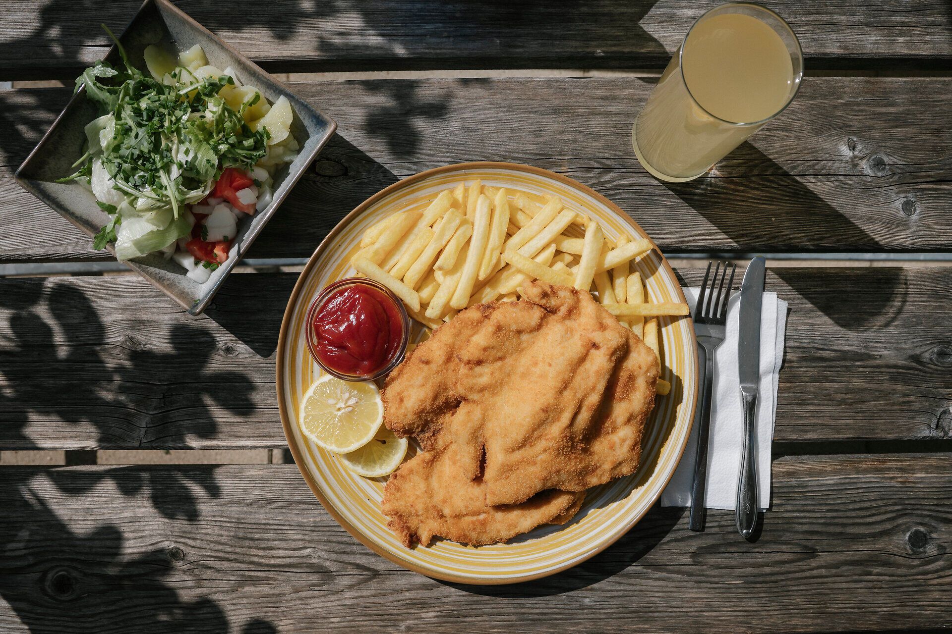 Schnitzel sült krumplival, salátával és itallal egy faasztalnál a Damböckhaus étteremben, a Schneebergnél