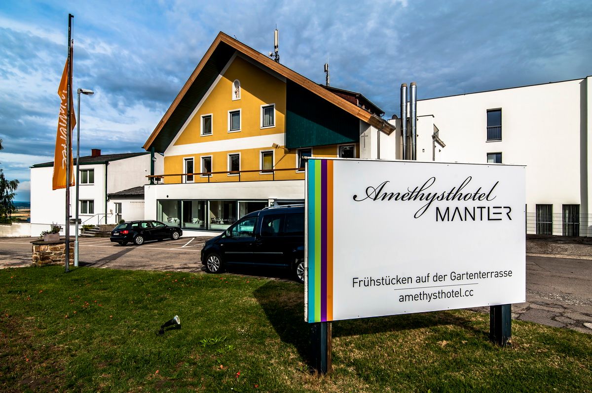 Az Amethysthotel Mantler külső nézete a parkolóval és a táblával.