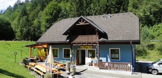 Kék épület, fából készült erkéllyel és terasszal, fákkal körülvéve.