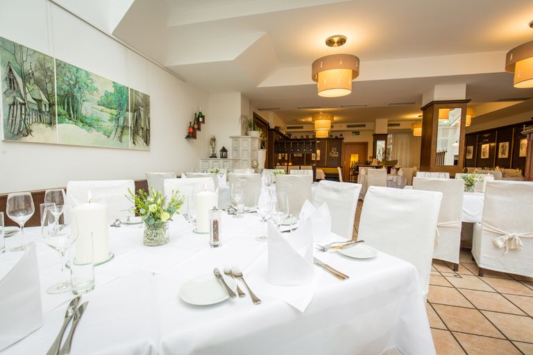 Der Wintergarten mit einem gedeckten Tisch und weißen Stühlen.