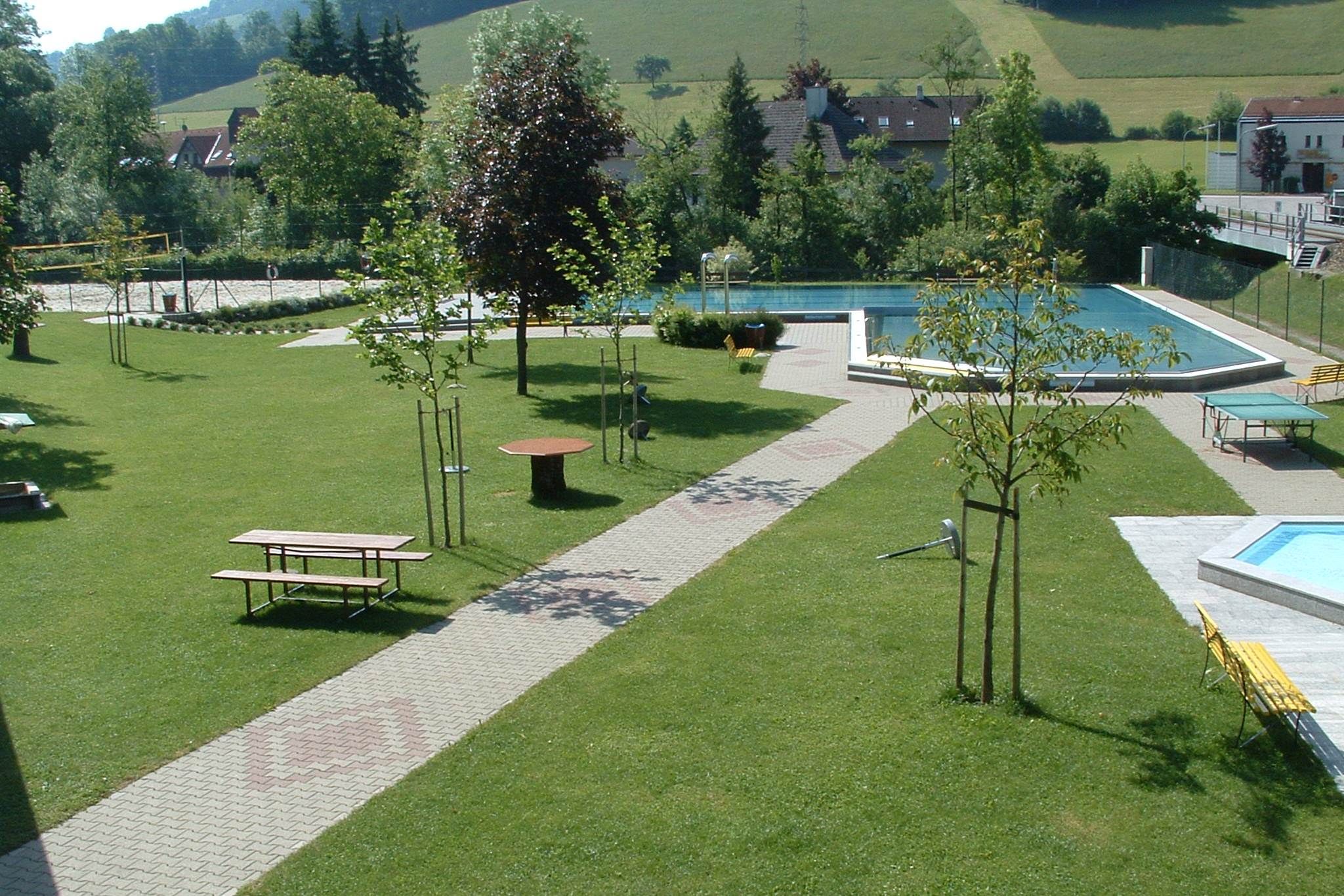Zöld park medencével és padokkal.