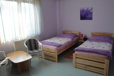 Egyszerűen berendezett szoba két egyszemélyes ággyal, egy kis asztallal és két székkel.
