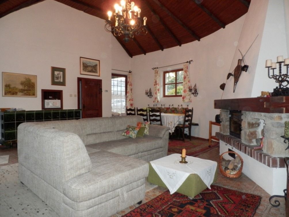 Hangulatos nappali szürke kanapéval, kandallóval és étkezőasztallal. Rusztikus dekoráció és fagerendás mennyezet.