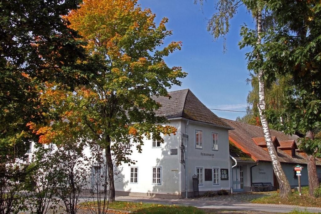 Fehér épület "Heimatmuseum" felirattal, körülötte őszi levelekkel borított fák.