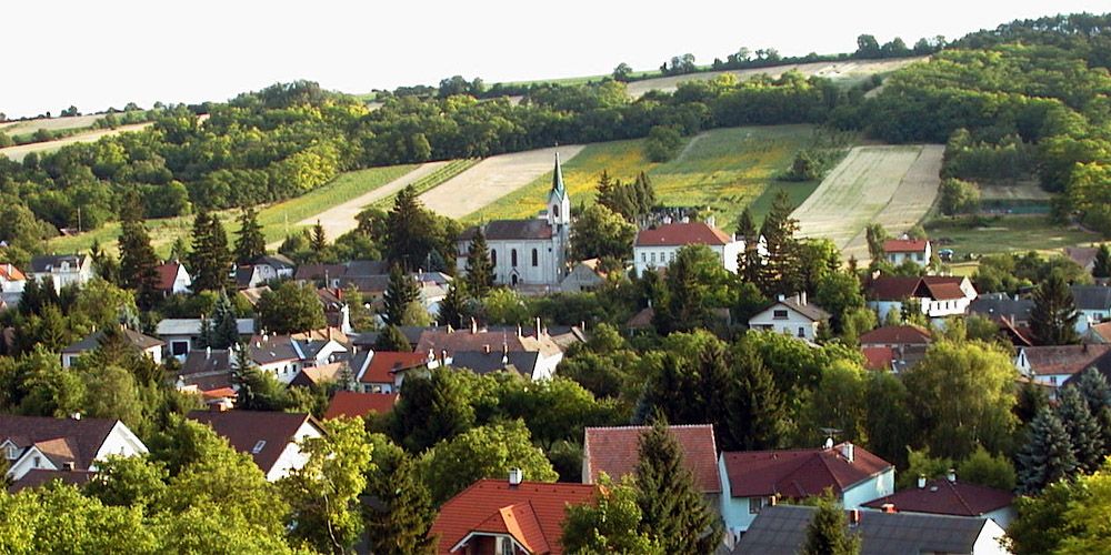 Unterolberndorf panorámája a templommal és a környező házakkal a zöld dombok előtt.