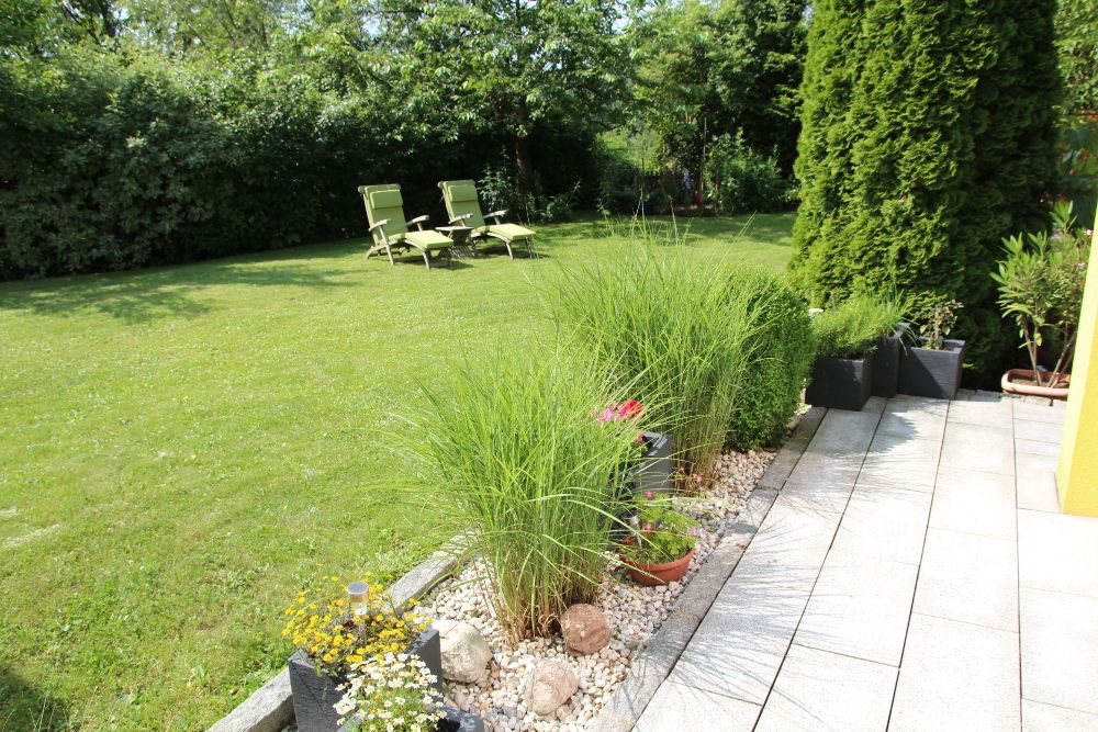 Kert pázsittal, nyugágyakkal és ültetett kerttel.