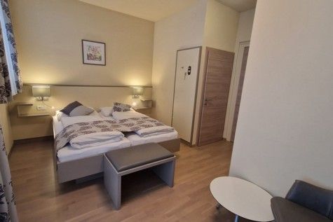 Hotelszoba franciaággyal, fapadlóval és modern berendezéssel.