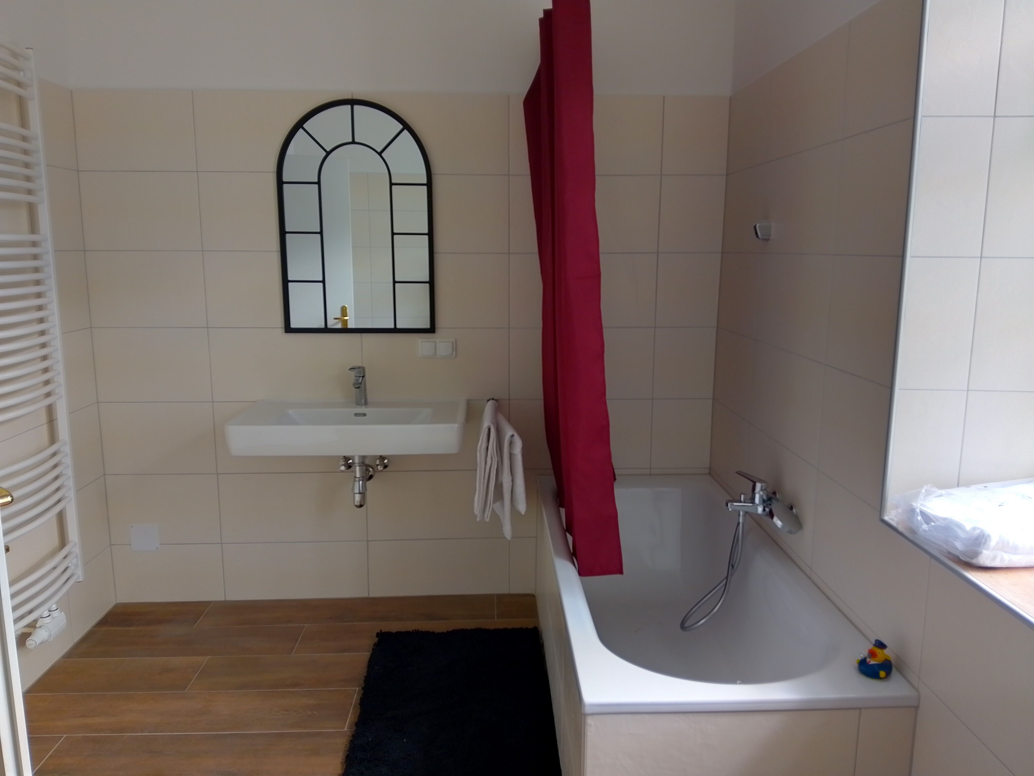 Modern fürdőszoba káddal, mosdóval és tükörrel.