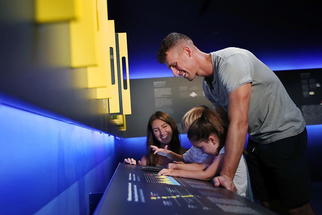 Egy család interakcióba lép egy múzeumi kiállítással.