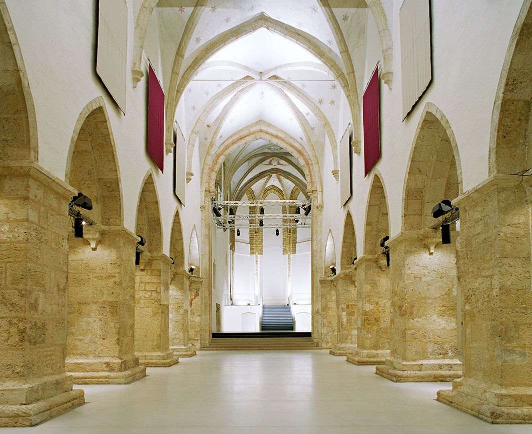 A kremsi minoriták templomának belső nézete gótikus boltívekkel és modern világítással.