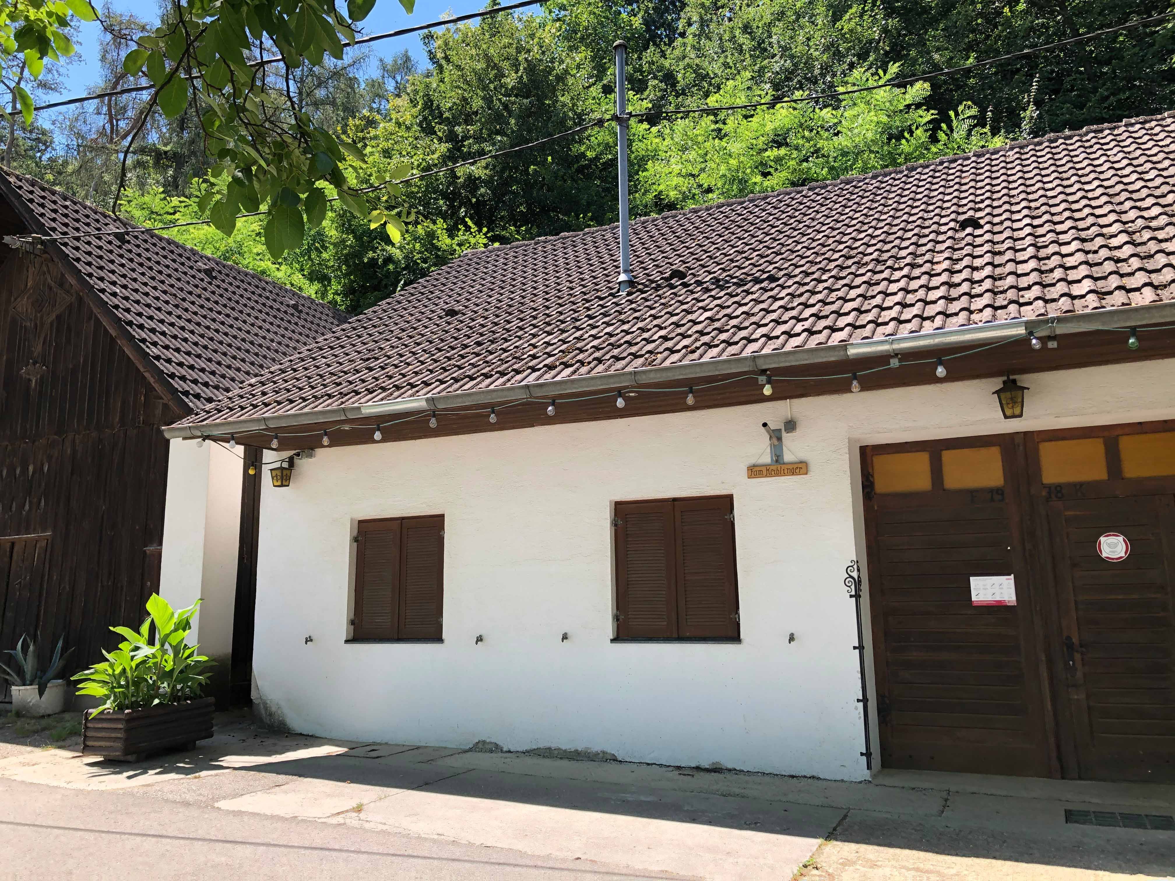 Egy borozó külső nézete fehér homlokzattal és faajtóval.