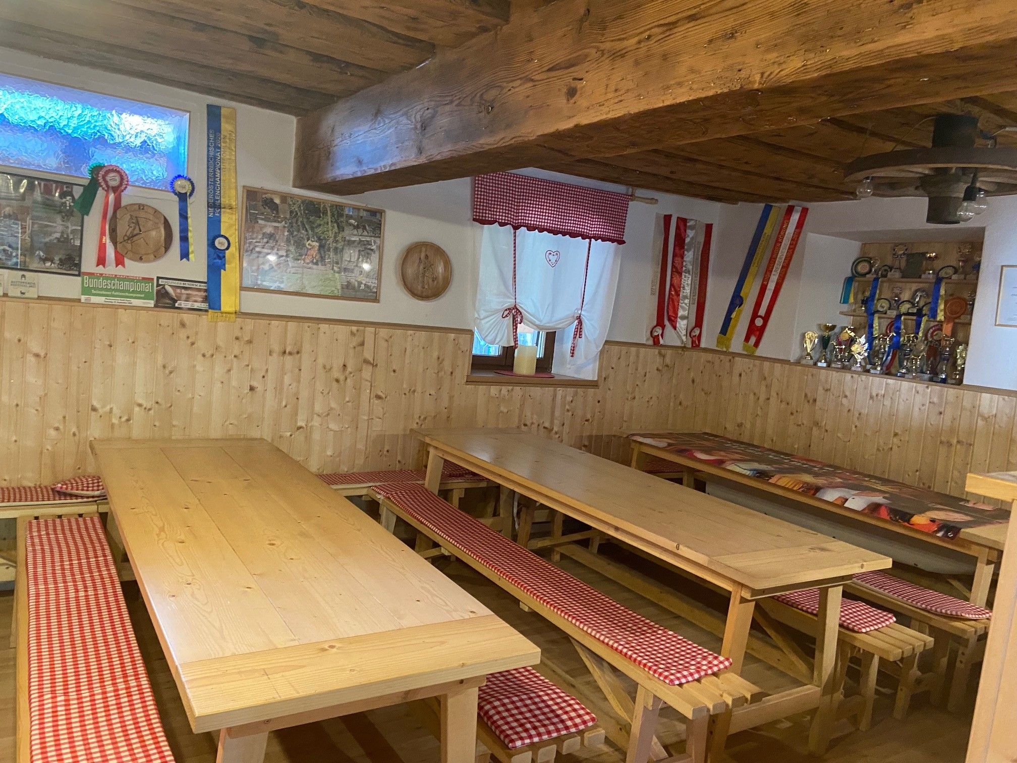 Hangulatos közös helyiség faasztalokkal, padokkal és dekorációkkal a falakon.