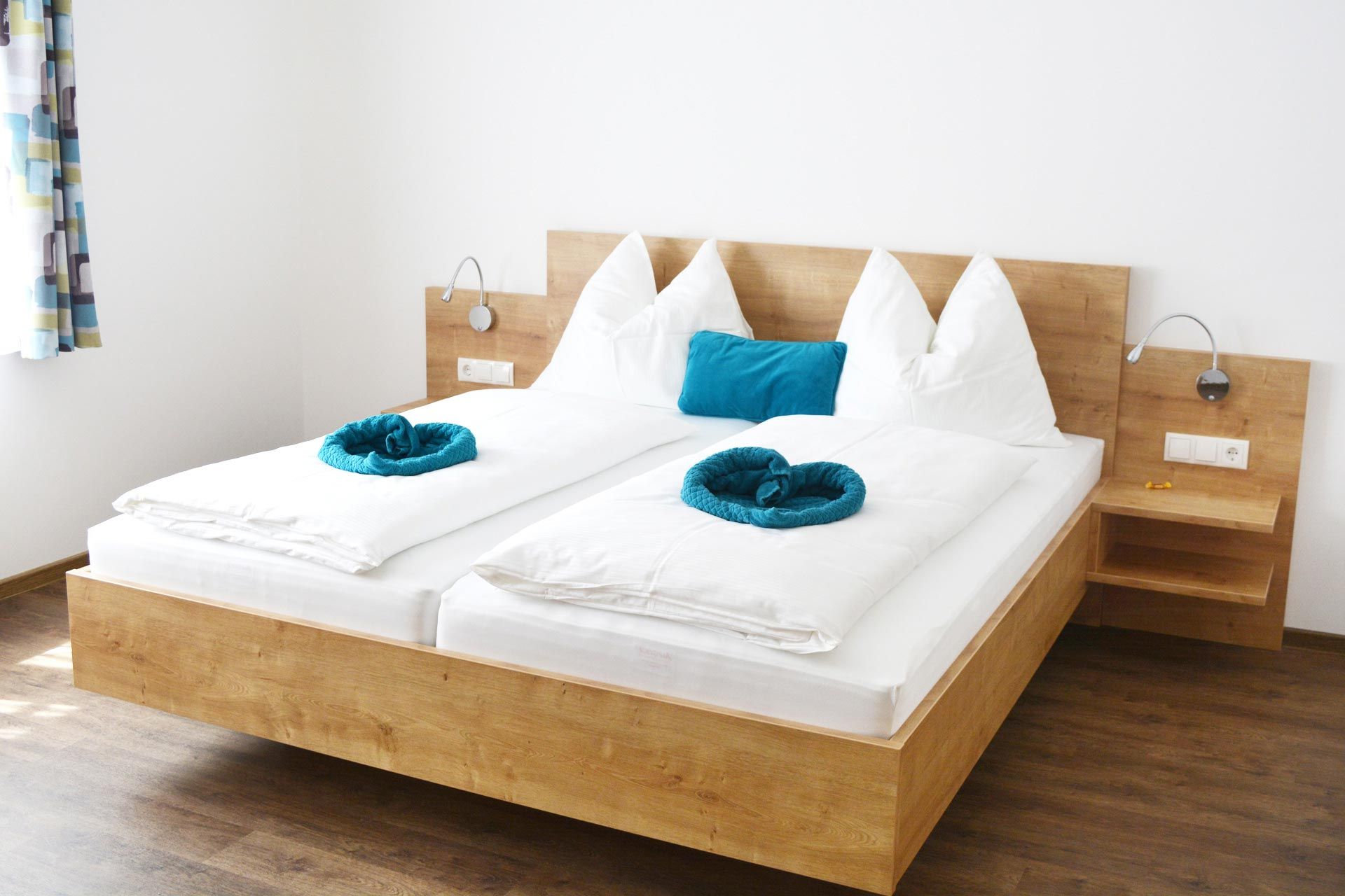 Modern vendégszoba franciaággyal, fehér paplanokkal és kék párnákkal.