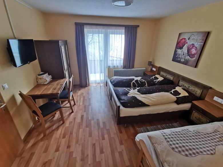 Hangulatos hálószoba franciaággyal, asztallal, székekkel és erkélykapcsolattal.