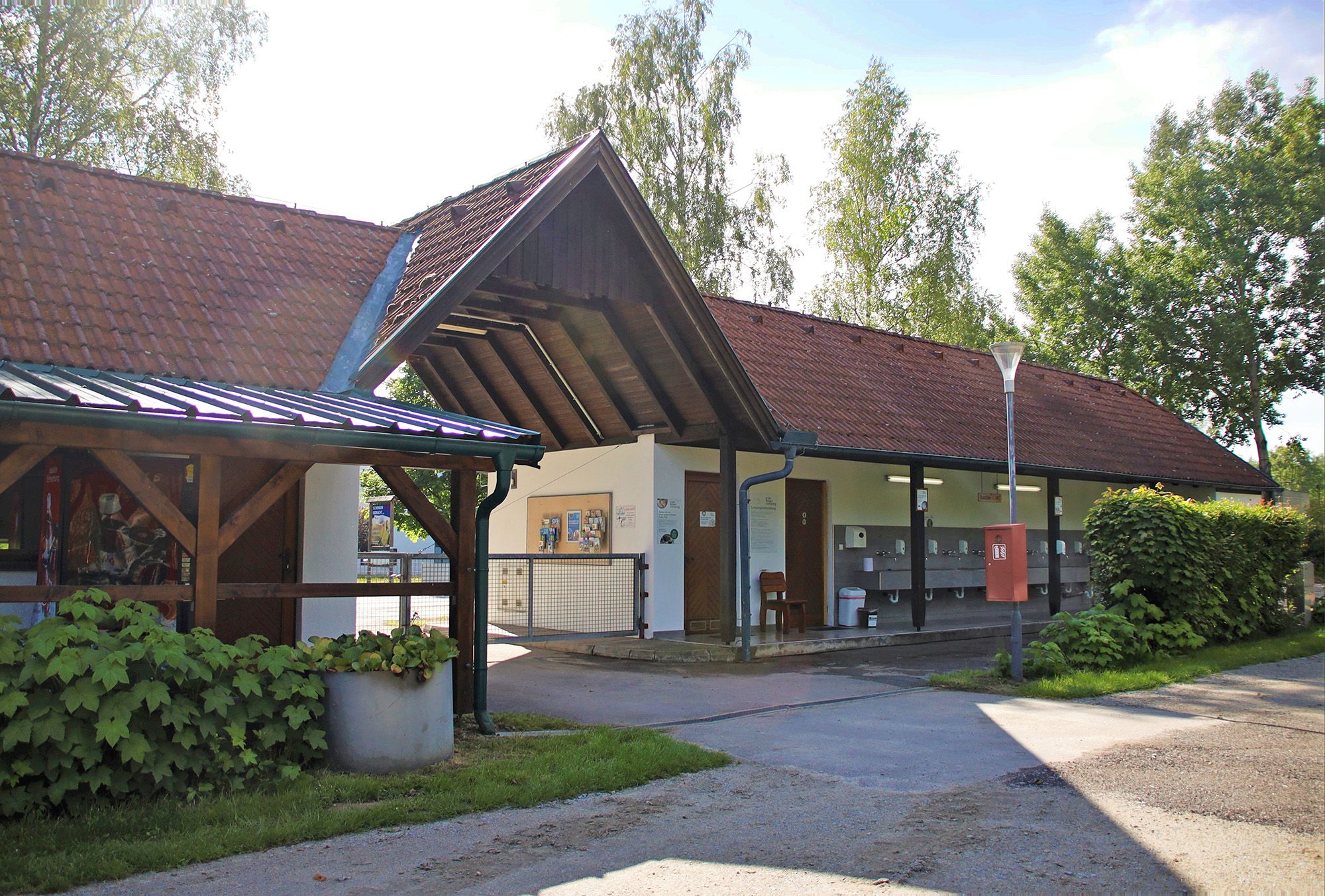 Egy épület külső nézete vörös cseréptetővel és kültéri mosdókagylókkal.