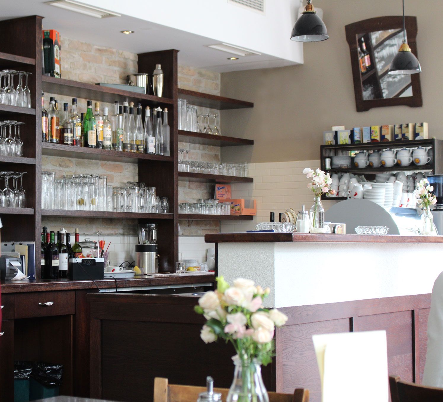 Egy bár belső nézete, poharakkal és üvegekkel teli polcokkal, virágokkal a pulton.