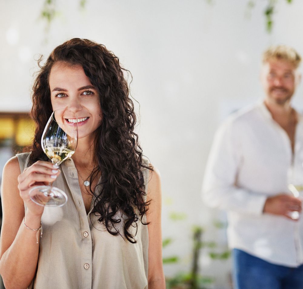 Két ember áll egy borszaküzletben, és egy személy tanácsokat ad nekik. A háttérben borosüvegekkel teli polcok láthatók.