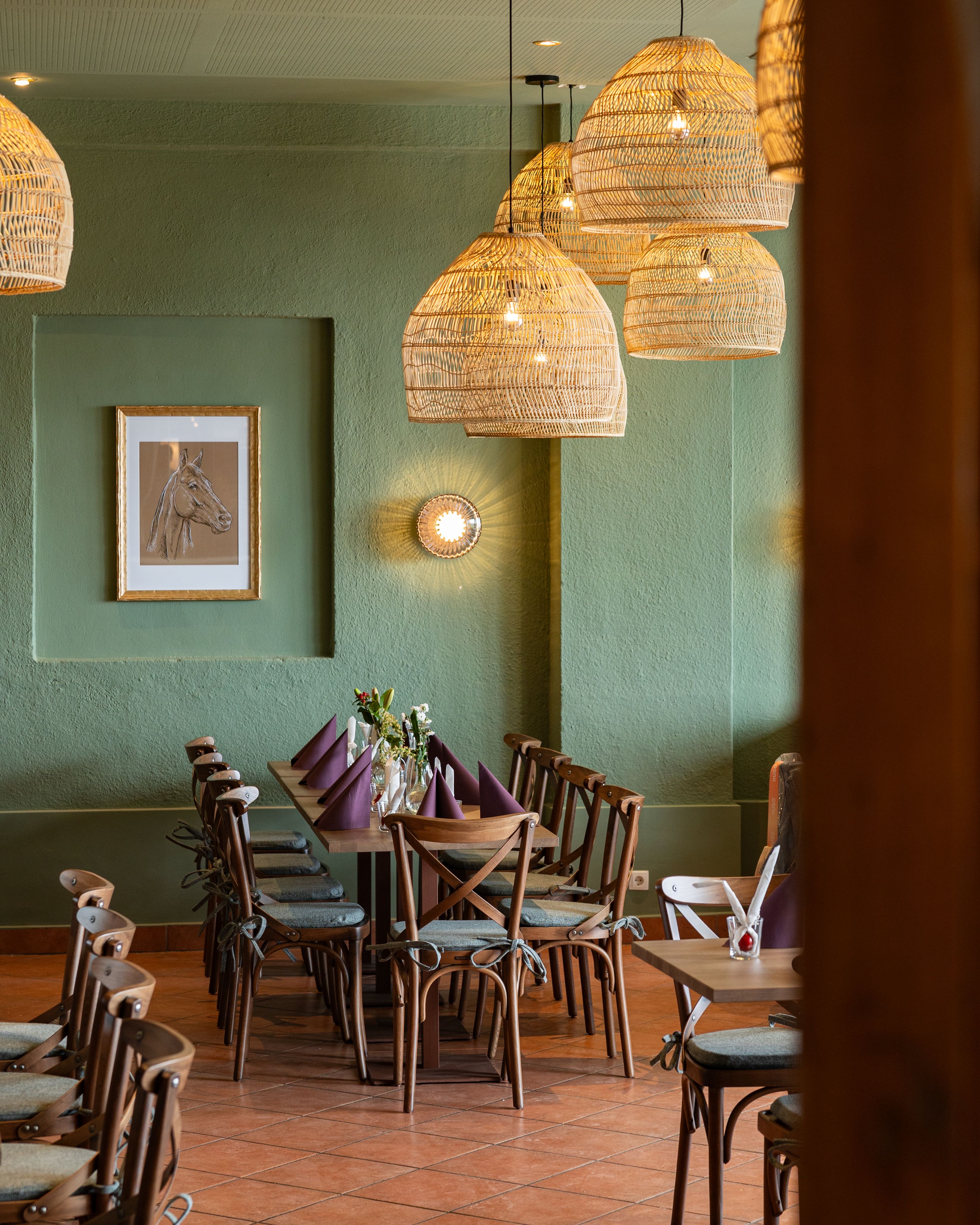 Hangulatos étkezőhelyiség fa asztallal, székekkel és fonott lámpákkal.