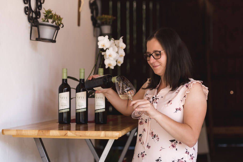 Nő bort tölt egy pohárba.