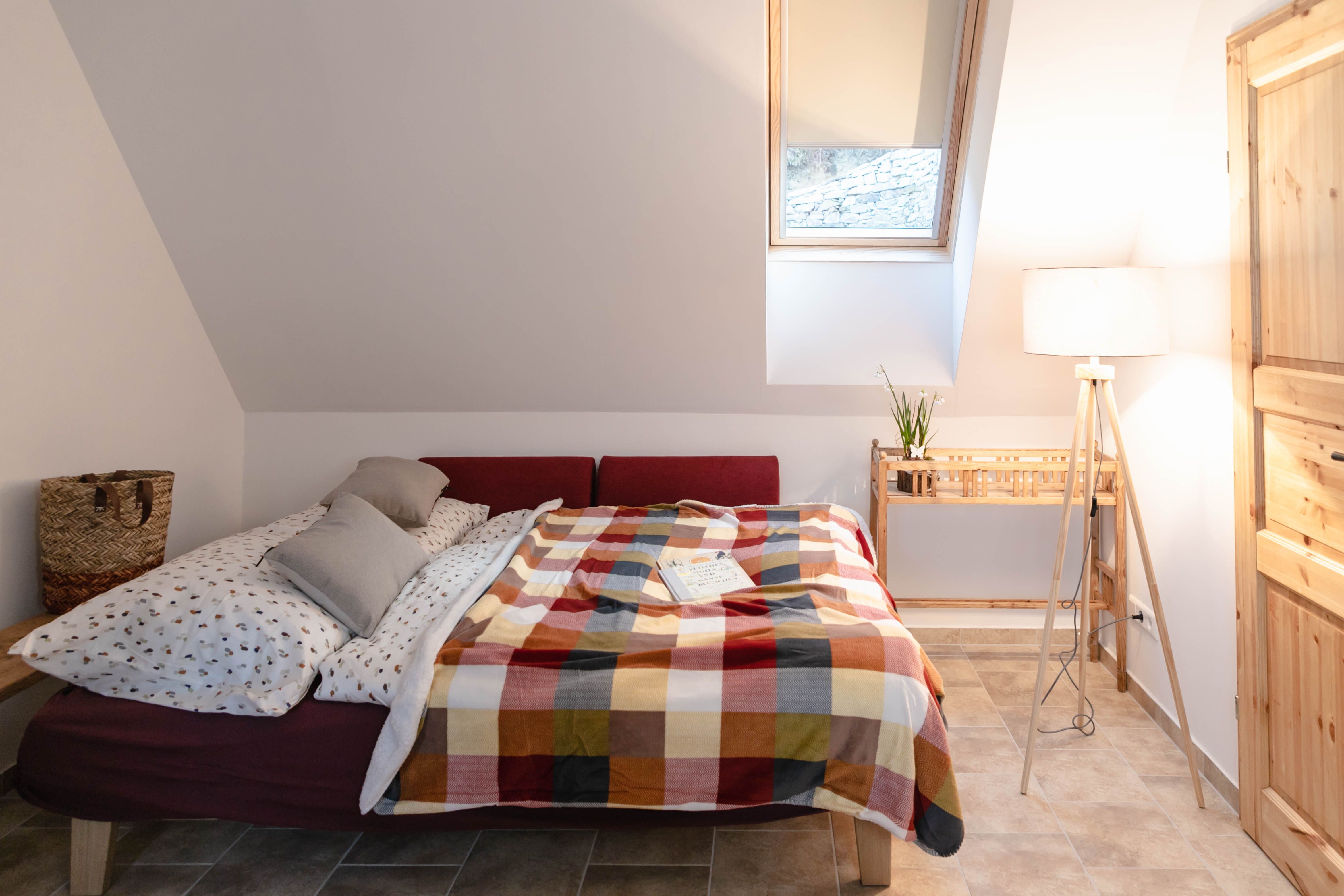 Hangulatos hálószoba ággyal, színes takaróval és olvasólámpával.