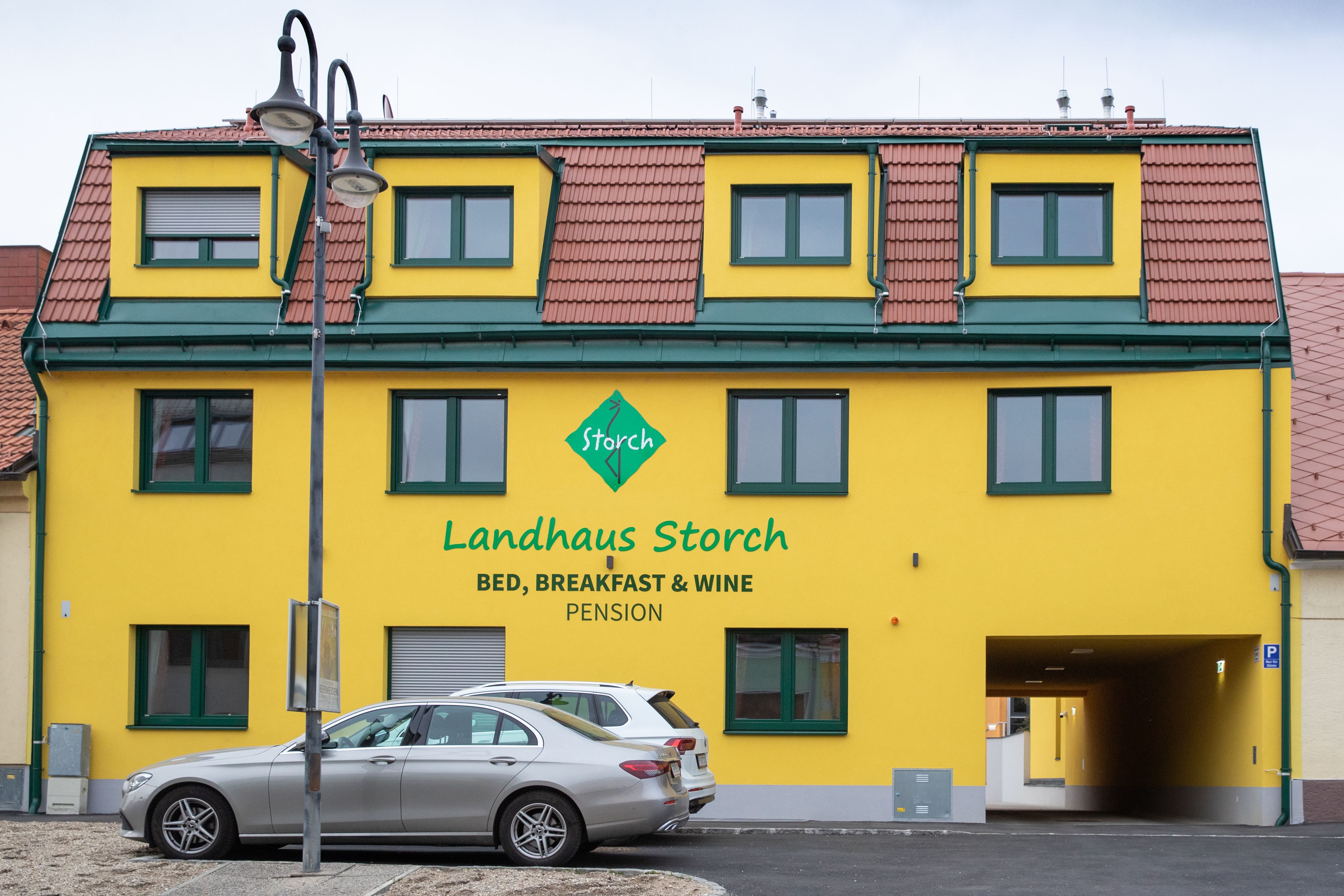 "Landhaus Storch" feliratú sárga épület, előtte parkoló autók.