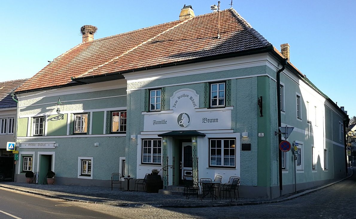 Zöld homlokzatú, hagyományos vendéglő, a "Zum weißen Rössl" névvel. Az épület előtt asztalok és székek találhatók.