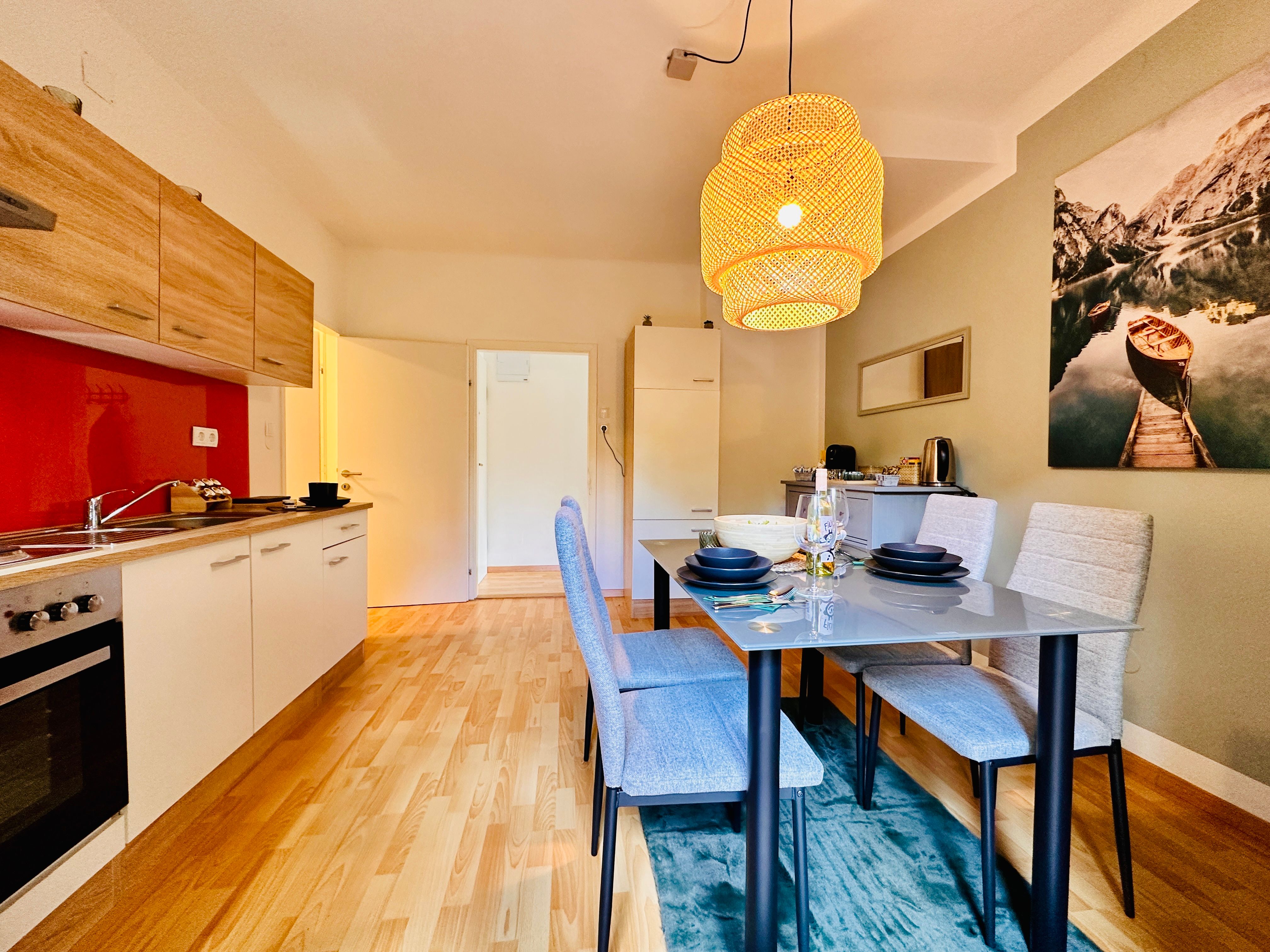 Modern konyha étkezőasztallal és függőlámpával.