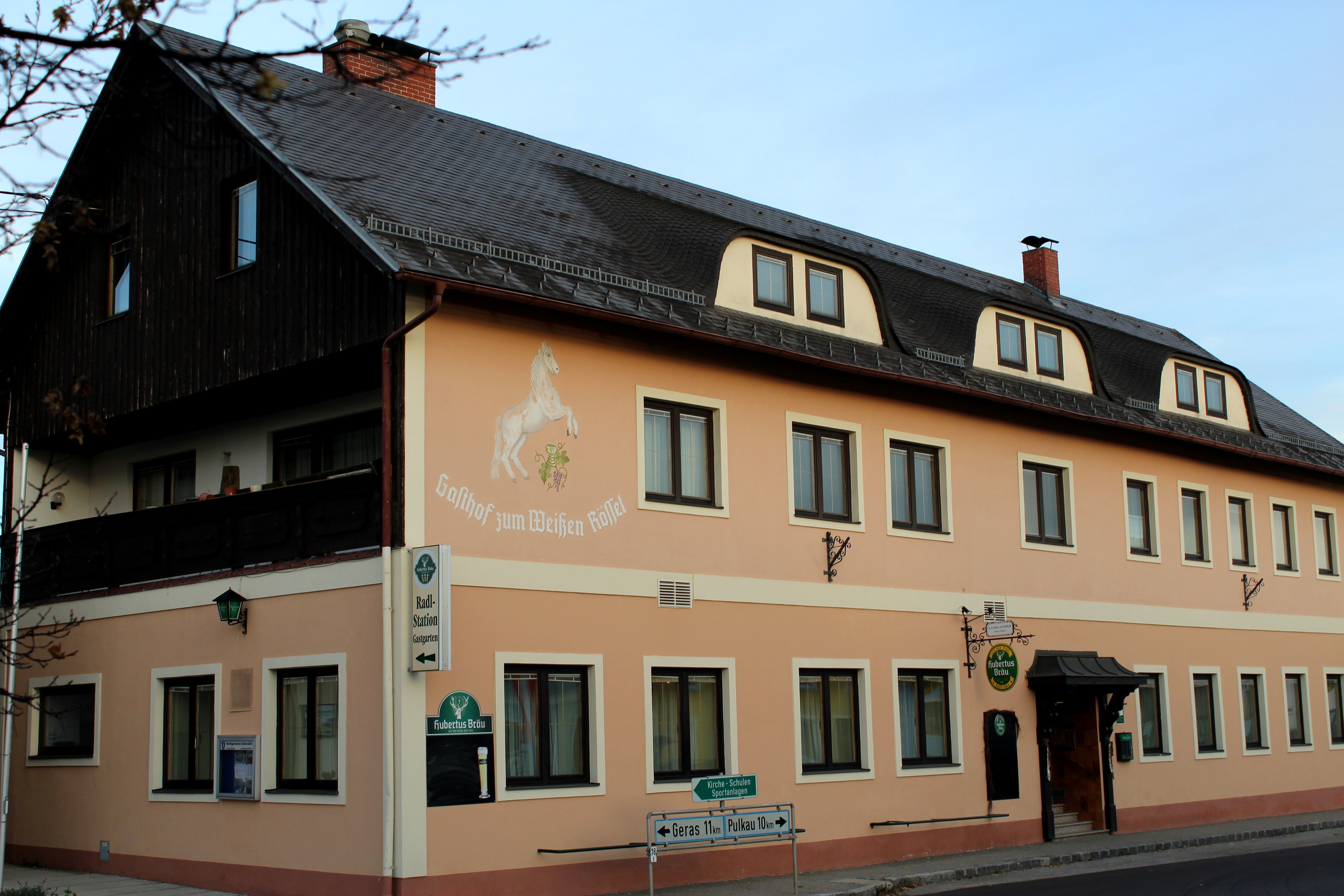 A "Zum weißen Rössel" vendéglő külső nézete bézs színű homlokzattal és lófestéssel.