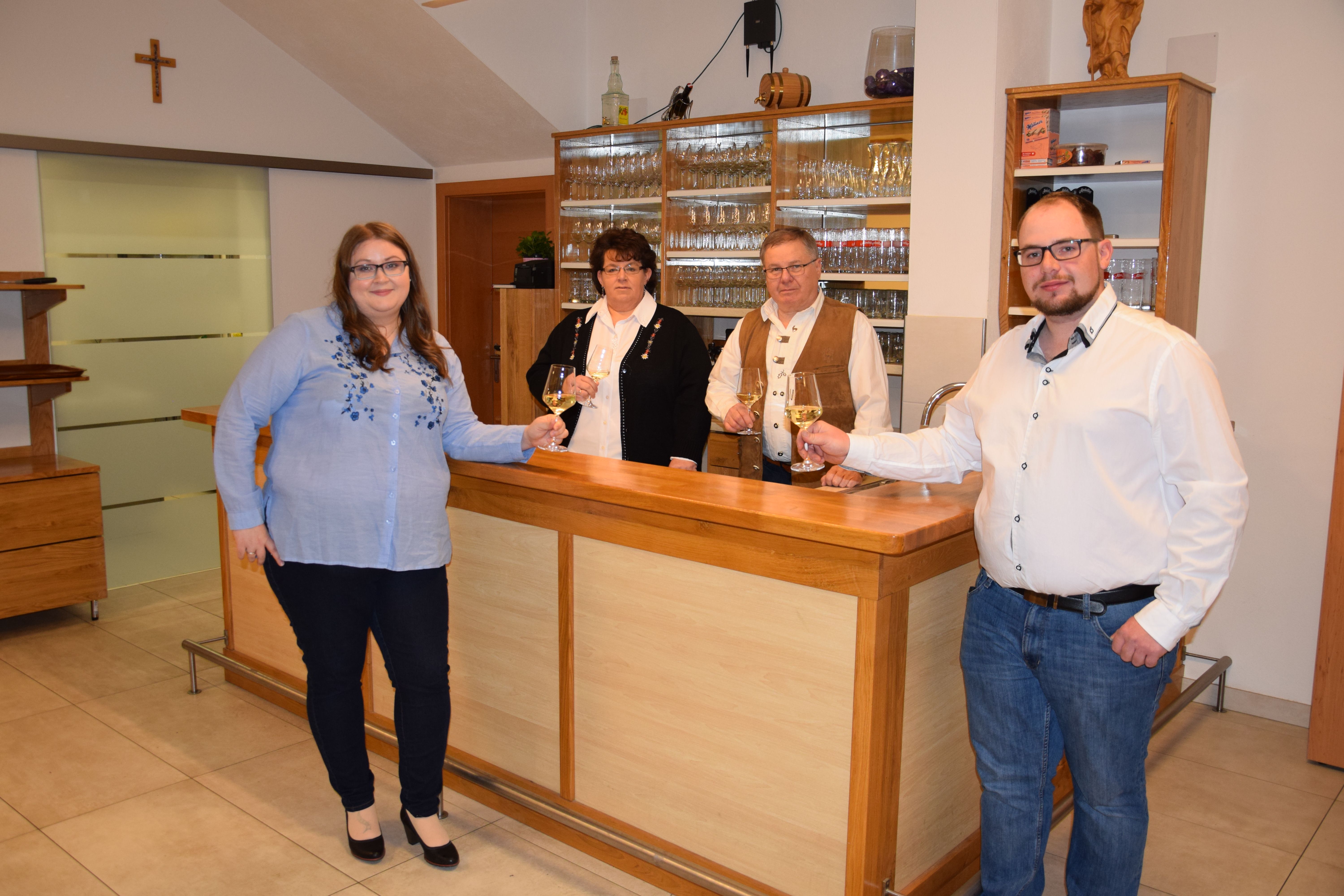 Négy ember áll a bárpultnál, kezükben borospoharakkal.