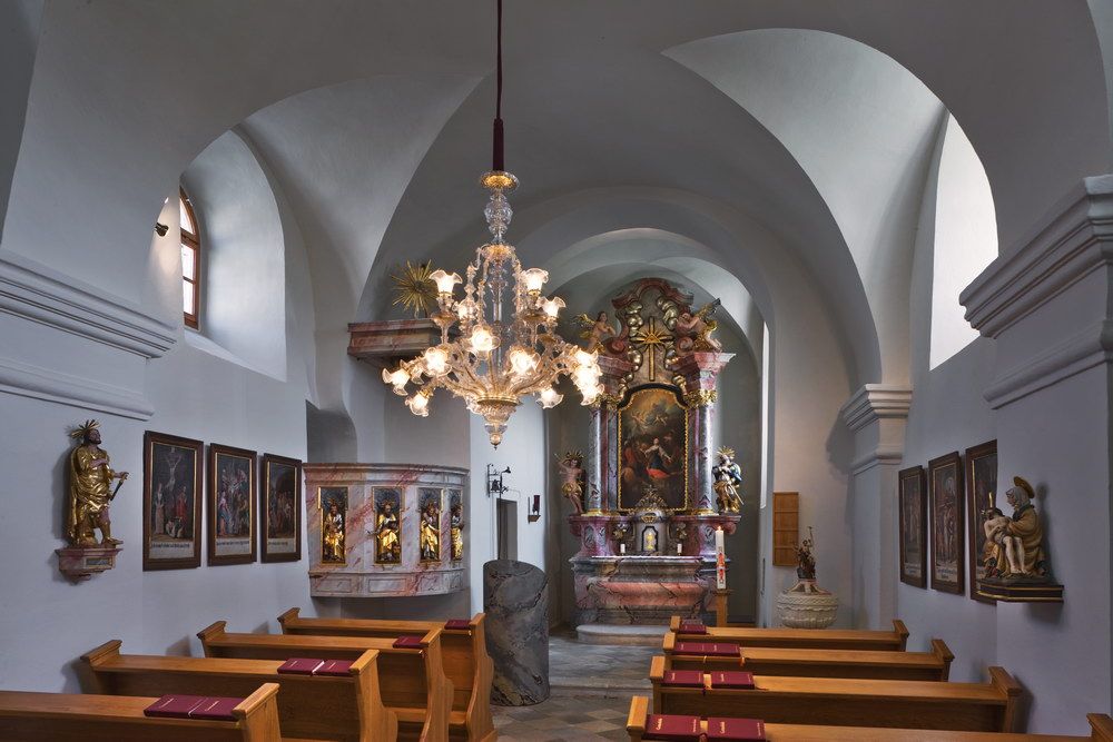 Egy barokk templom belső nézete oltárral, festményekkel és csillárral.