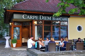 A Carpe Diem nevű kávézó külső nézete, emberek ülnek a szabadtéri asztaloknál.