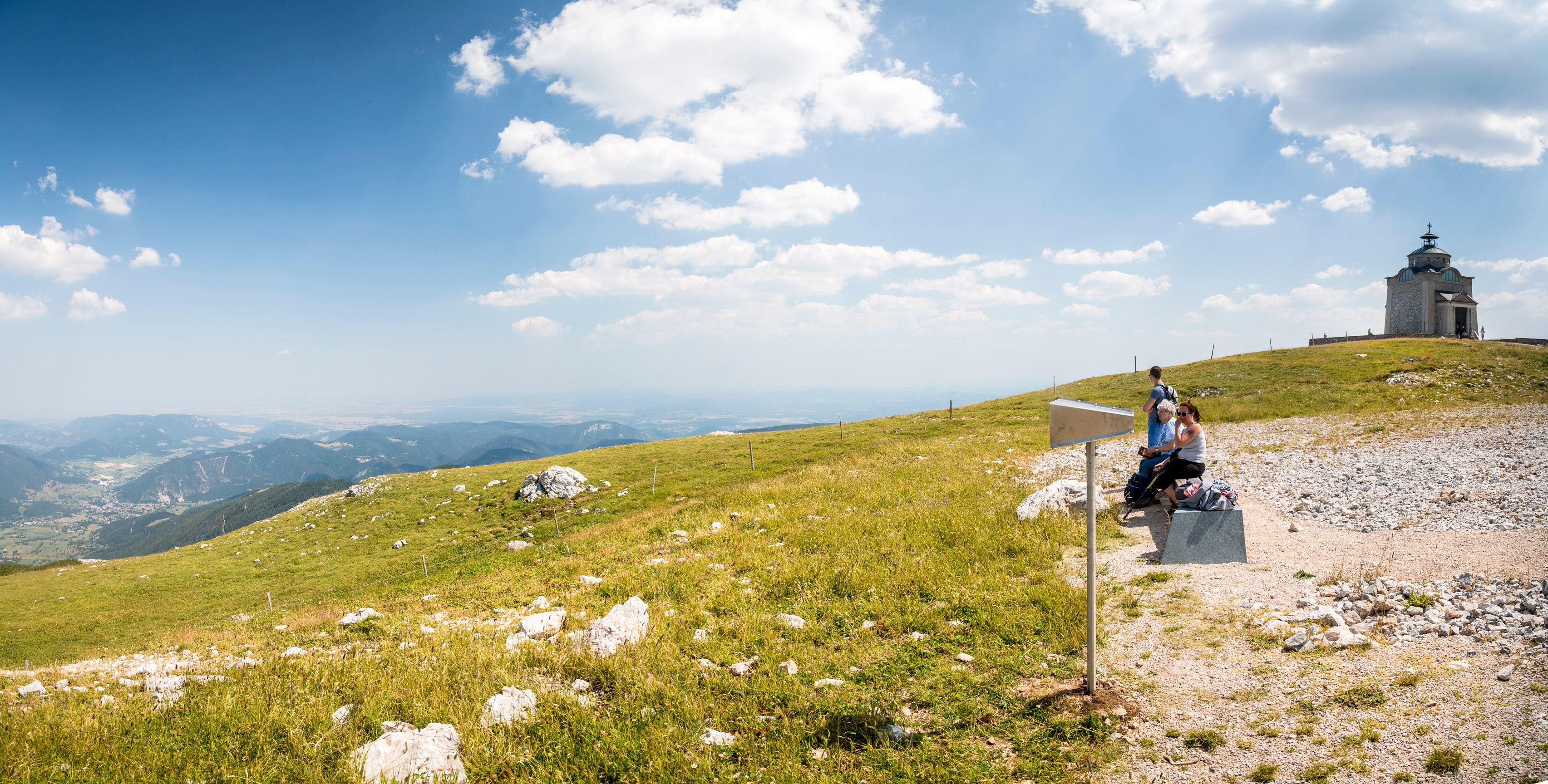 Az Erzsébet-templom panorámaképe a Schneebergen, előtérben túrázókkal.