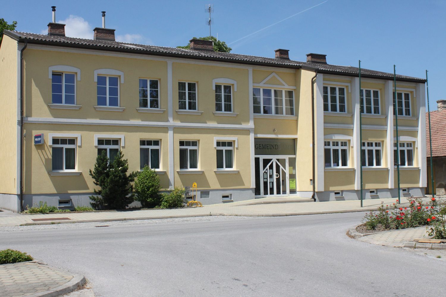 Sárga épület "Gemeindeamt" felirattal és több ablakkal.