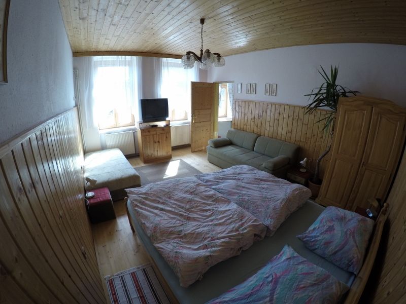Hangulatos hálószoba franciaággyal, kanapéval, TV-vel és fabútorokkal egy nyaraló apartmanban.