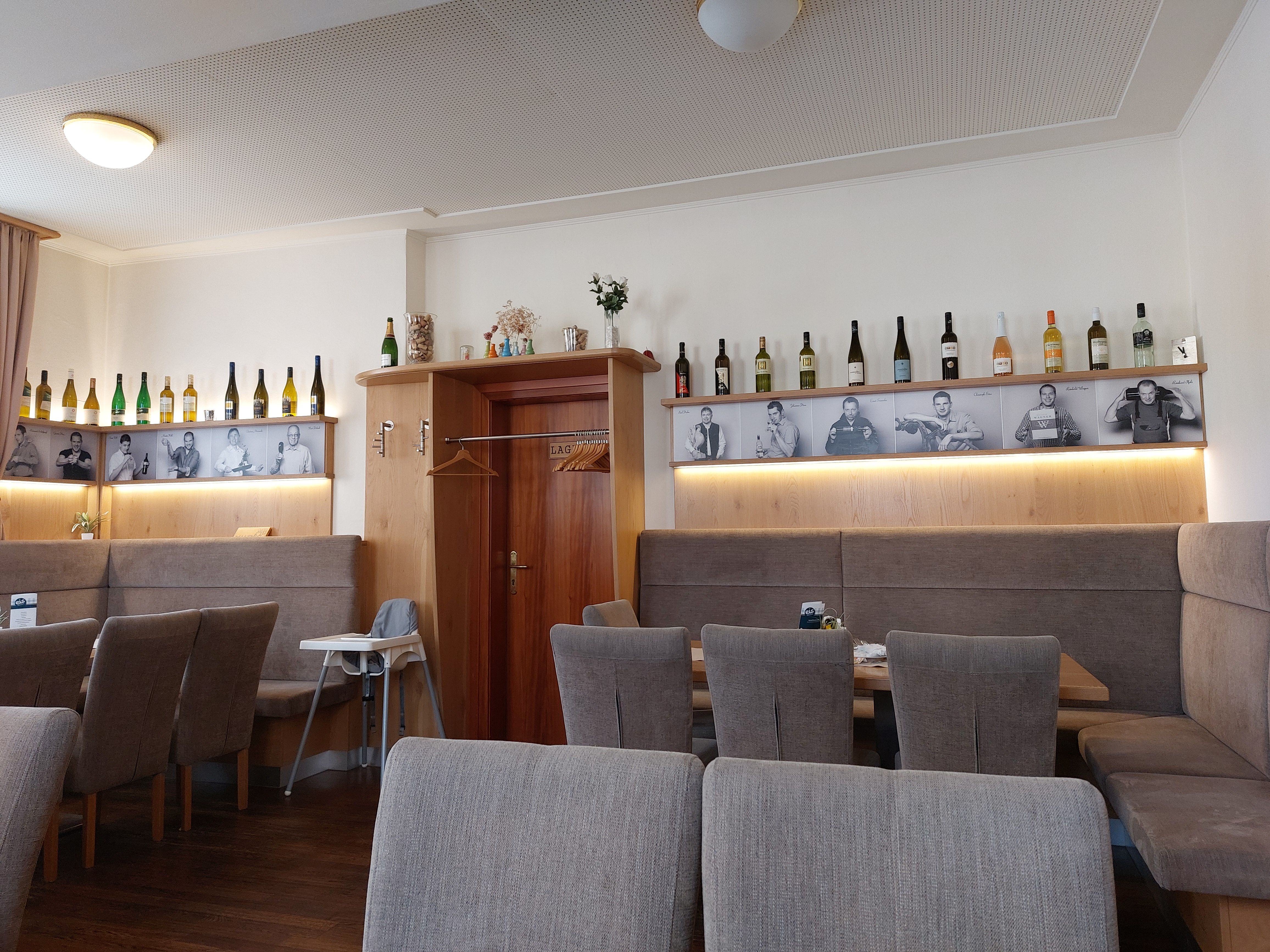 Egy étterem belső nézete borosüvegekkel és fekete-fehér fotókkal a falon.