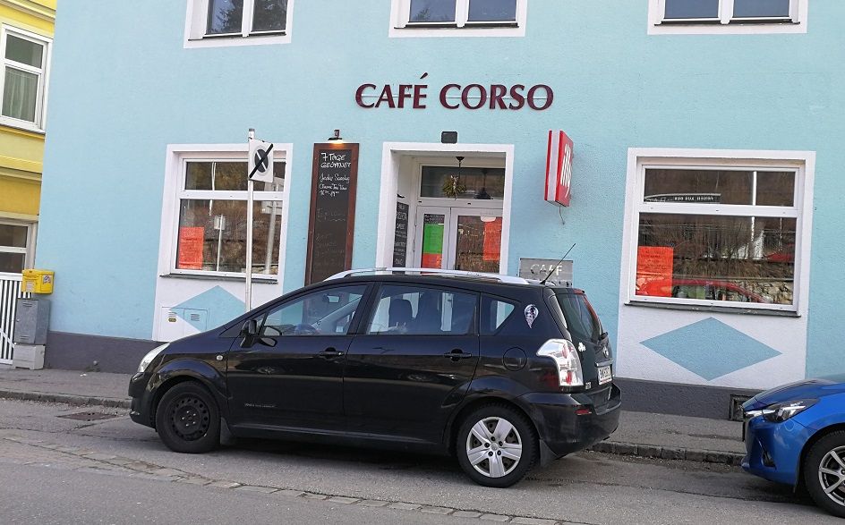 A Café Corso külső nézete, előtte parkoló autóval.