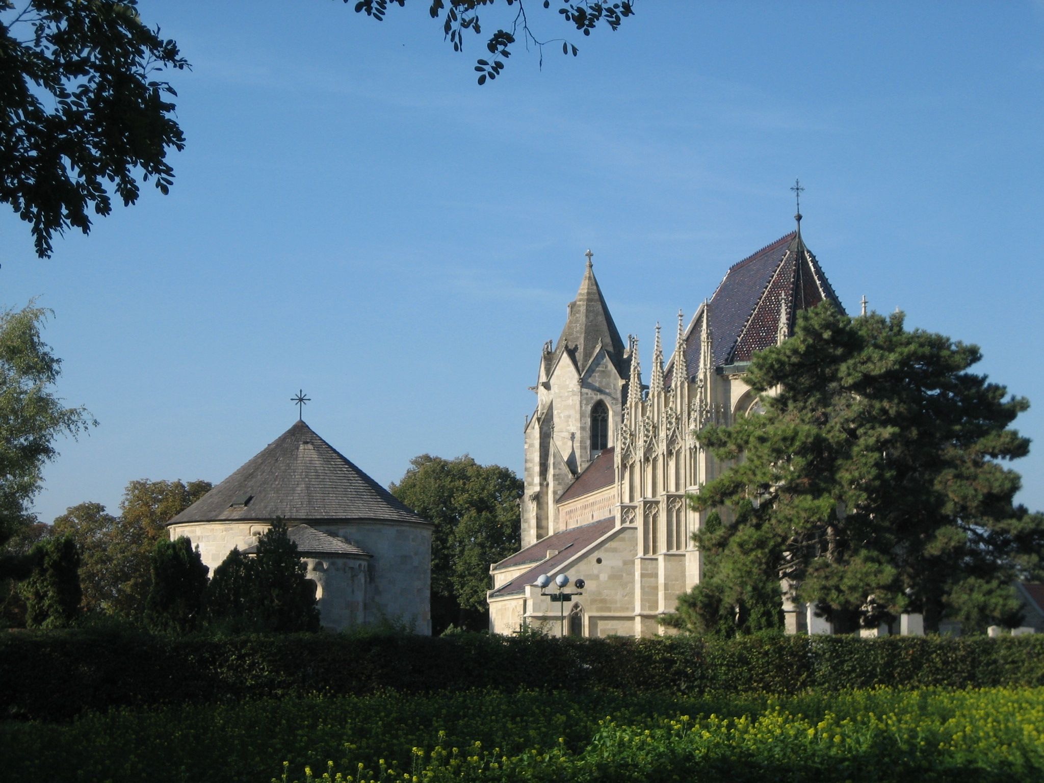 A Bad Deutsch-Altenburg-i Szent Mária-templom kék éggel és fákkal az előtérben.