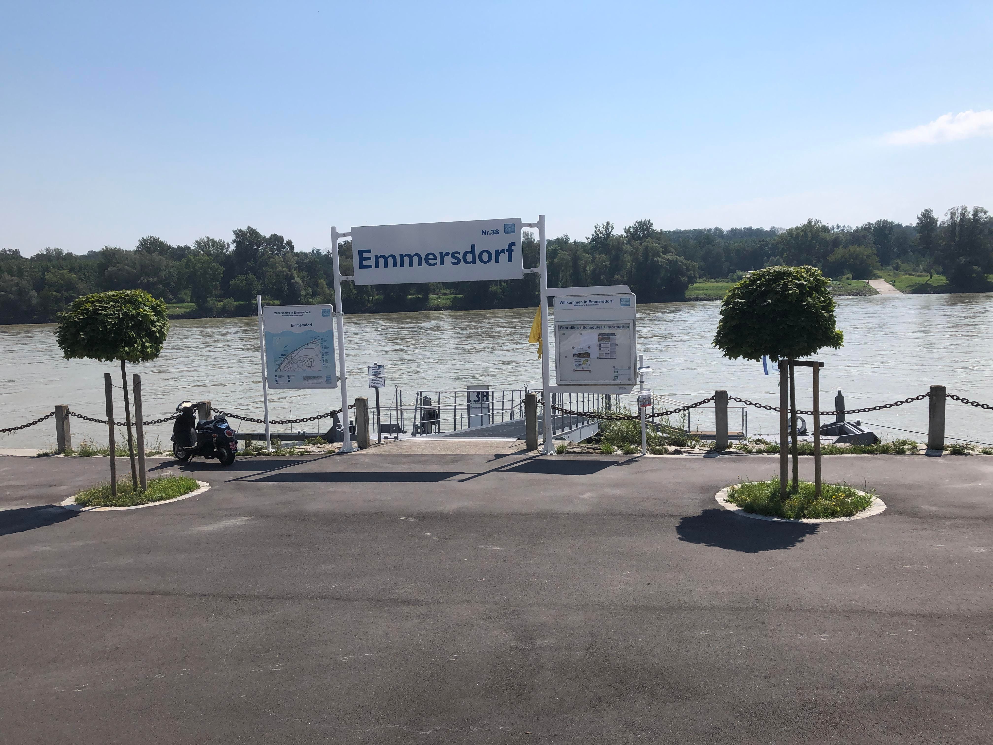 Emmersdorfi stég a Dunán, jelzőtáblákkal és fákkal.
