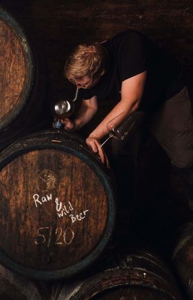 In einem geheimnisvollen Keller, umgeben von alten Holzfässern, wird mit Hingabe ein einzigartiges Bier gebraut. Der sanfte Lichtschein und die rustikale Atmosphäre laden dazu ein, die Kunst des Brauens hautnah zu erleben und die Aromen der Natur zu genießen.