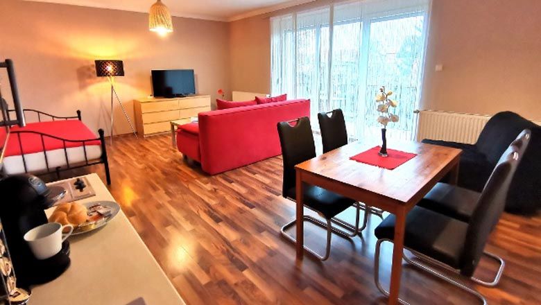 Modern nappali piros kanapéval, étkezőasztallal és síkképernyős TV-vel.